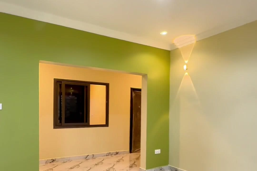 Living room of the apartment, with a green feature wall and marble-effect floor